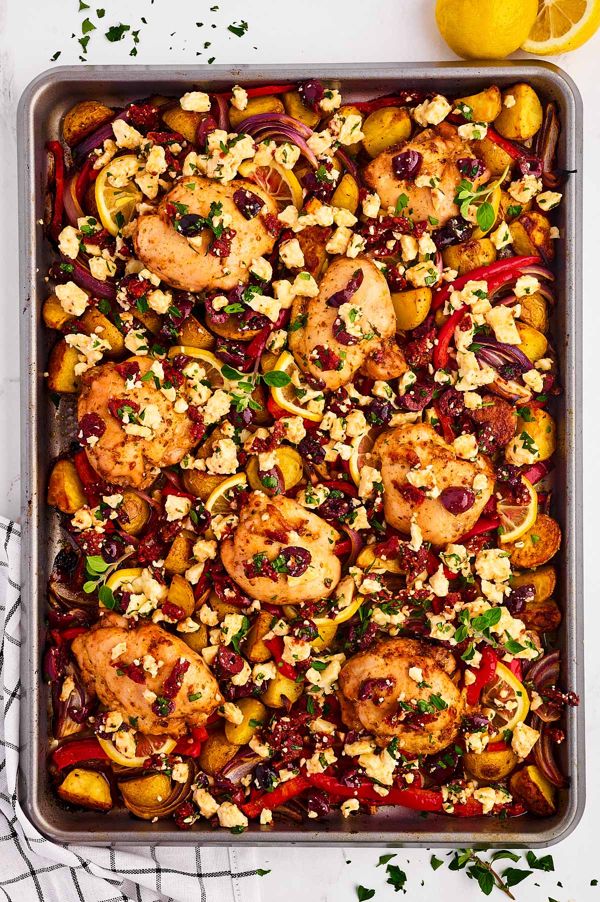 overhead view of greek chicken on sheet pan with vegetables