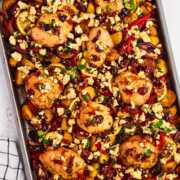 overhead view of greek chicken on sheet pan with vegetables and olives