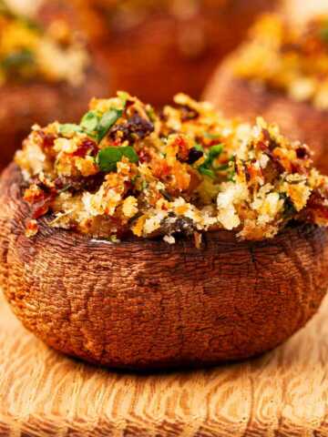 frontal view of stuffed mushroom on wooden chopping board