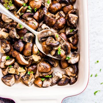 Garlic Butter Mushrooms in a Le Creuset casserole dish with a spoon.