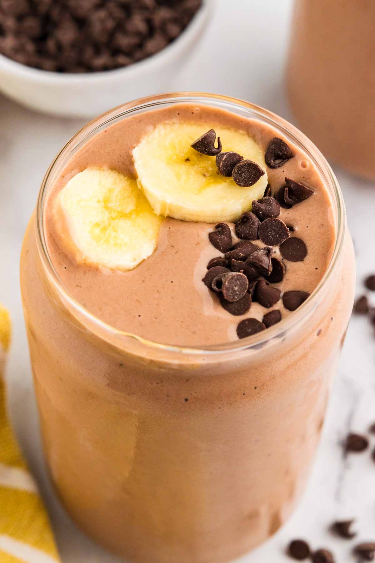 45° angle view of chocolate peanut butter in a glass with chocolate chips and banana slices