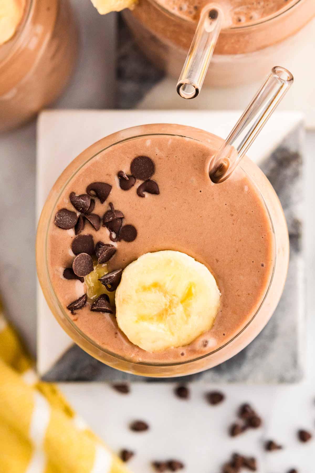 overhead view of chocolate peanut butter in a glass with chocolate chips and banana slices