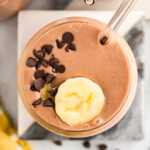 overhead view of chocolate peanut butter in a glass with chocolate chips and banana slices