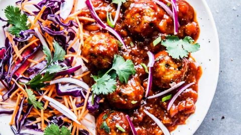 Pineapple BBQ Meatballs on a white plate with slaw and cilantro.