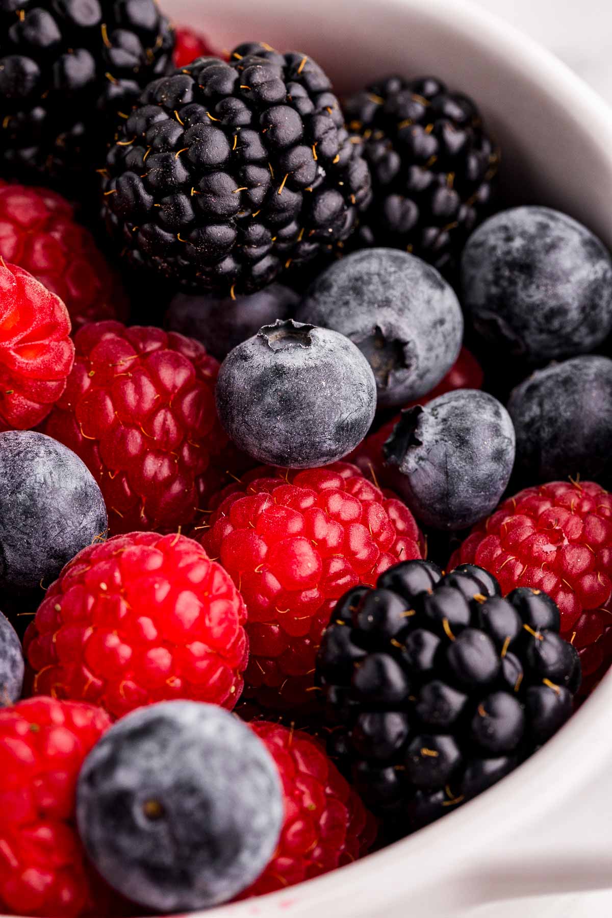 frontal close up view of frozen berries in white bowl