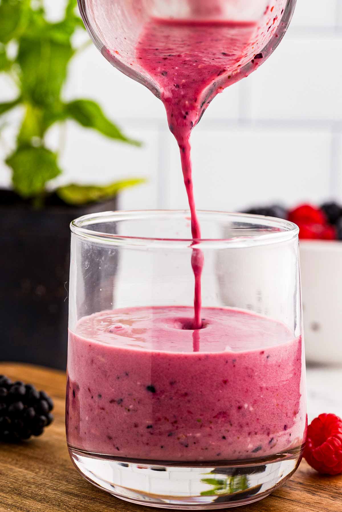 frontal view of berry smoothie being poured into a glass