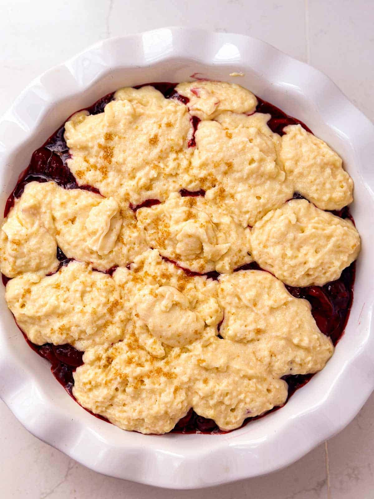 overhead view of unbaked cherry cobbler in fluted pie dish