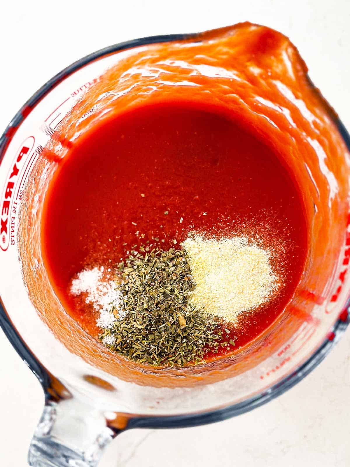 ingredients for tomato sauce in measuring jug