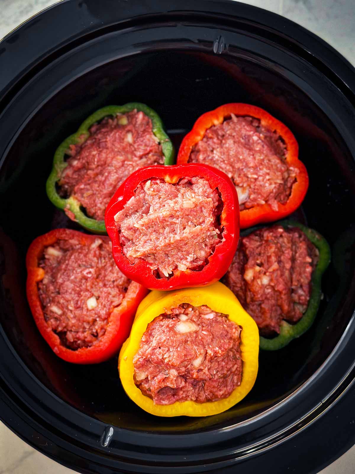 overhead view of uncooked stuffed peppers in crockpot
