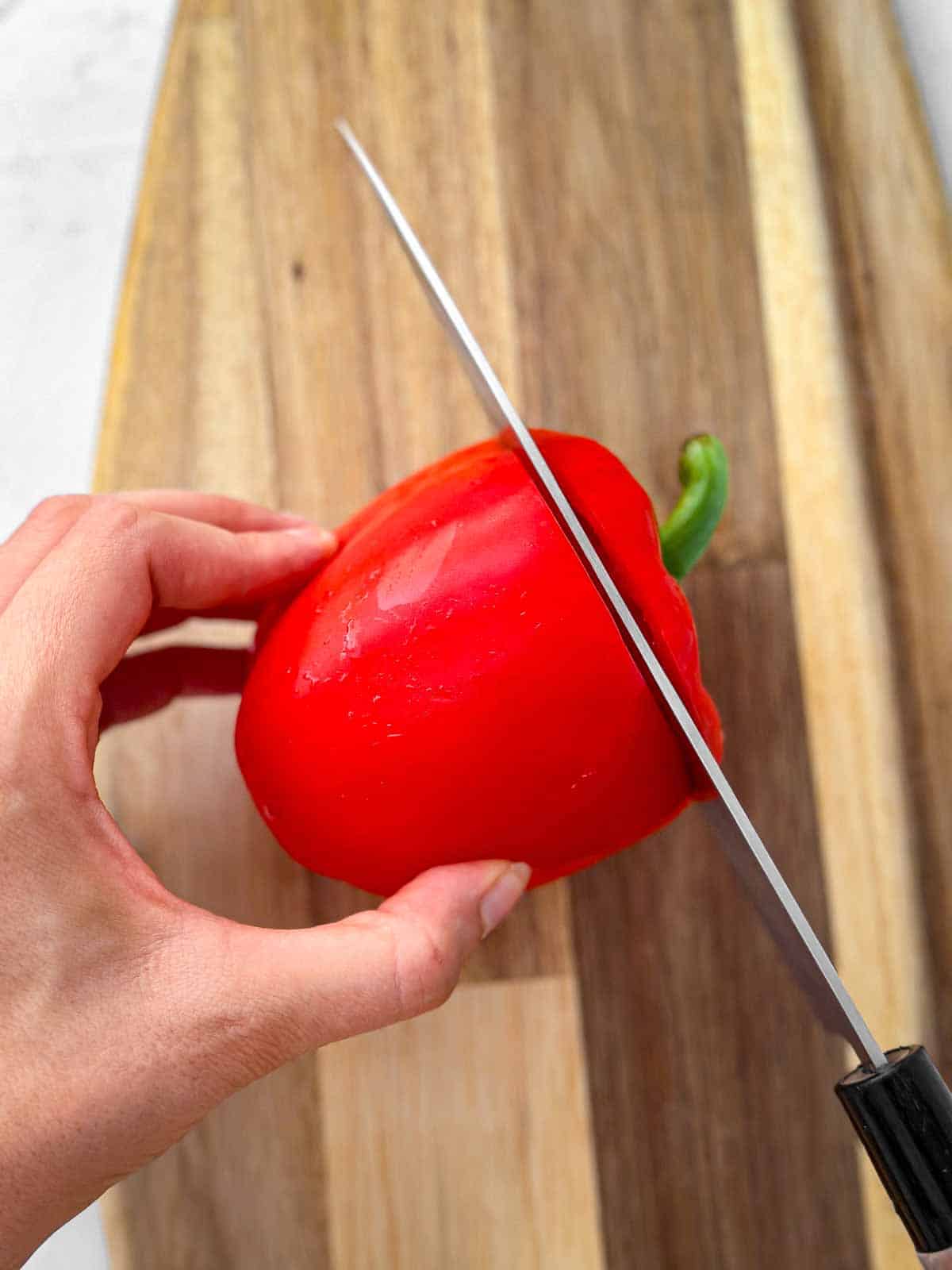 knife slicing off top of bell pepper