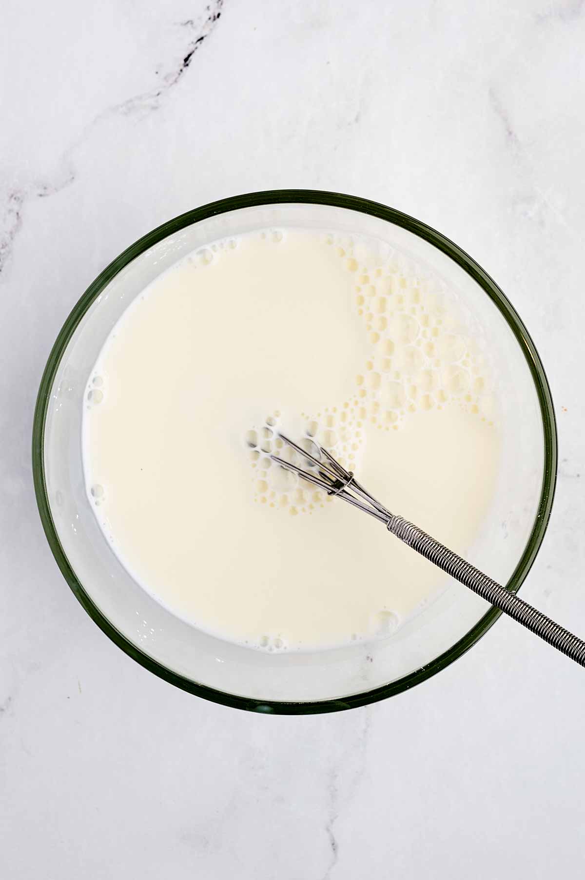 overhead view of cornstarch slurry in glass bowl with whisk