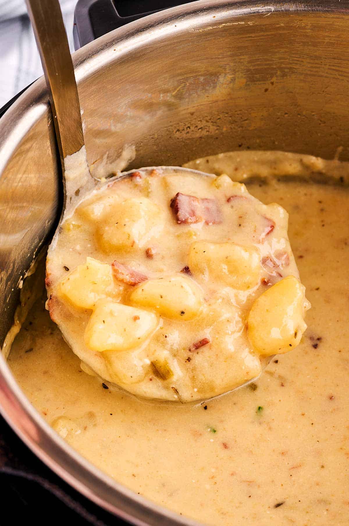 frontal view of ladle filled with potato soup inside instant pot