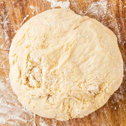 overhead view of pizza dough ball on wooden board