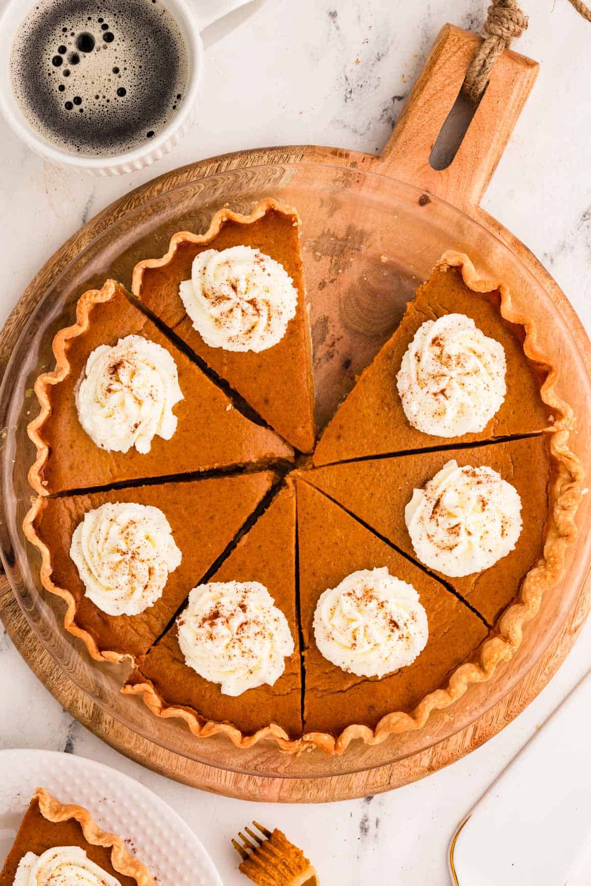 overhead view of sliced pumpkin pie decorated with whipped cream