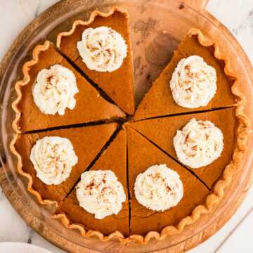 overhead view of sliced pumpkin pie decorated with whipped cream