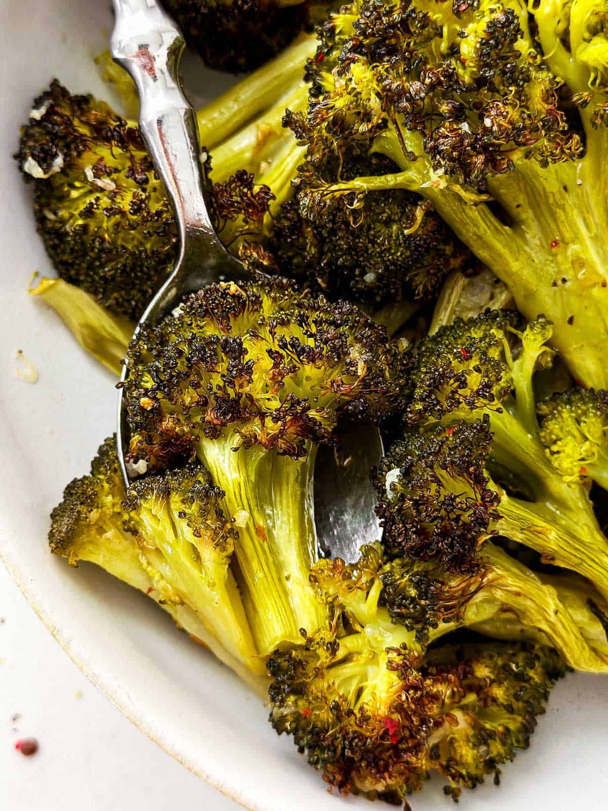 close up photo of roasted broccoli in white bowl