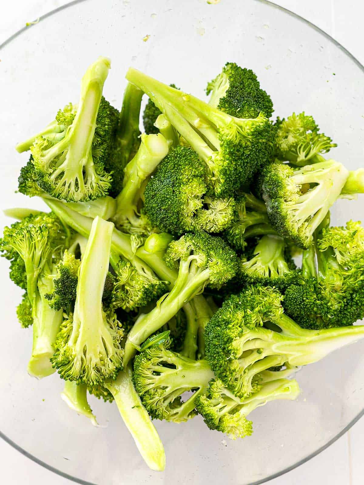 overhead view of glass bowl filled with raw broccoli florets