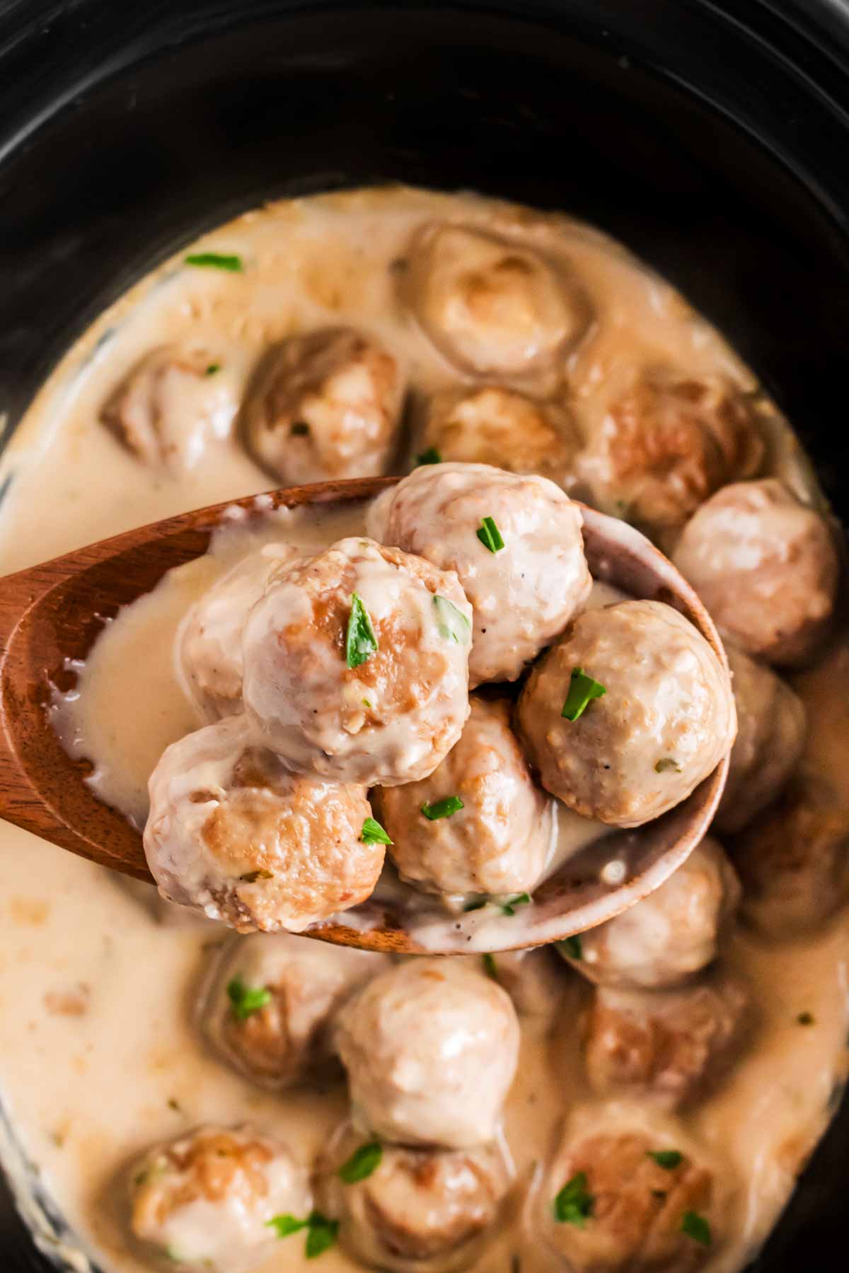 overhead view of slow cooker Swedish meatballs on wooden spoon