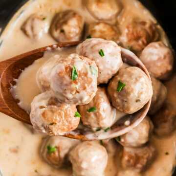 overhead view of slow cooker Swedish meatballs on wooden spoon