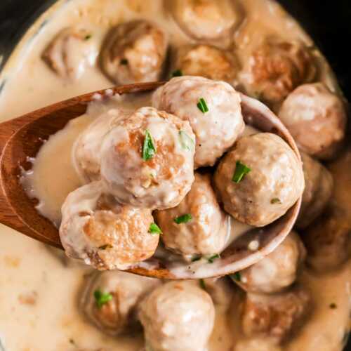 overhead view of slow cooker Swedish meatballs on wooden spoon