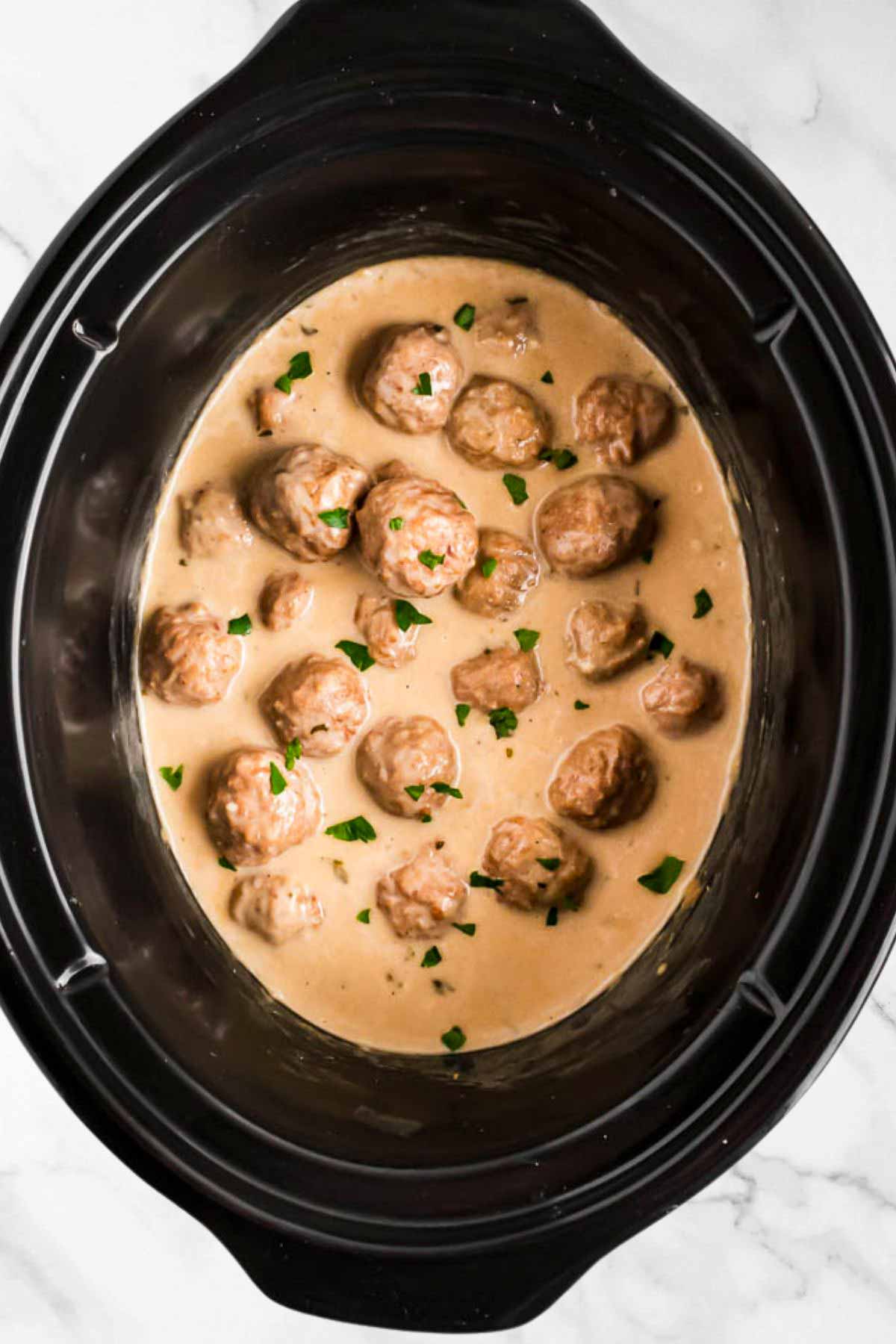 overhead view of Swedish meatballs in black crockery insert of slow cooker