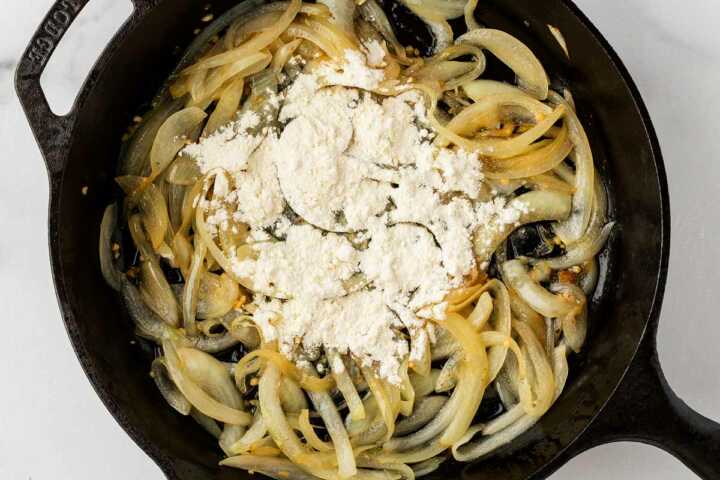 onions being sautéed in cast iron skillet with flour