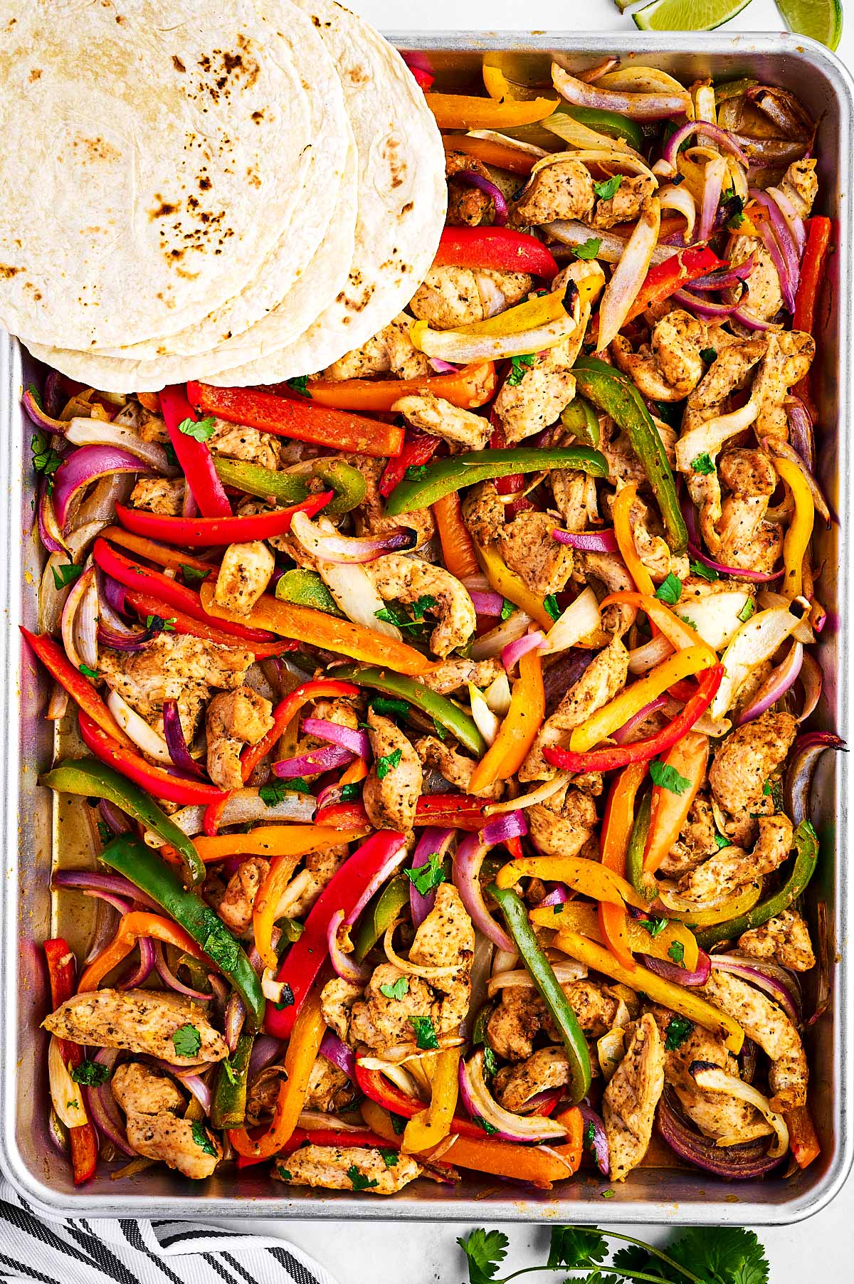 overhead view of chicken fajitas on sheet pan with tortilla wraps