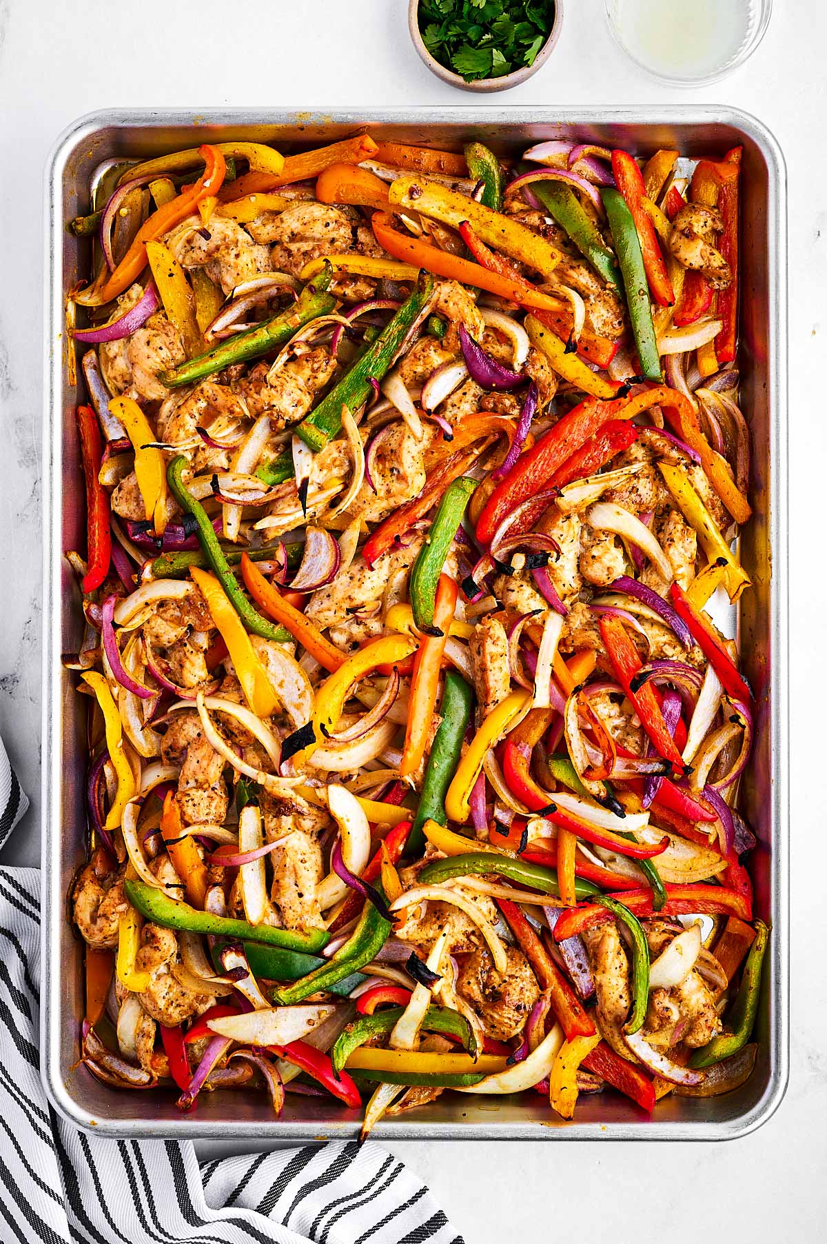 overhead view of cooked chicken fajitas on sheet pan