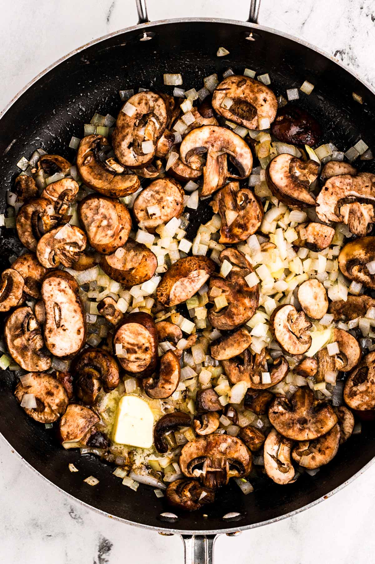 overhead view of sautéed onion and mushrooms in skillet