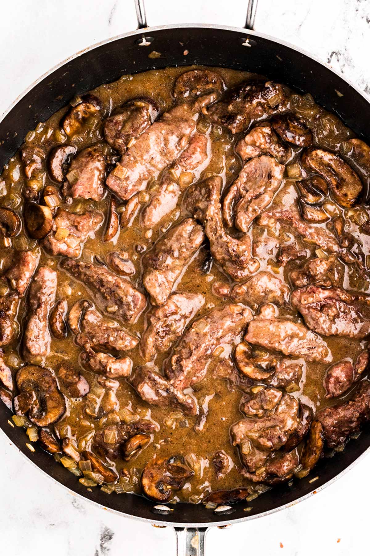 overhead view of beef stroganoff with beef stirred around in skillet