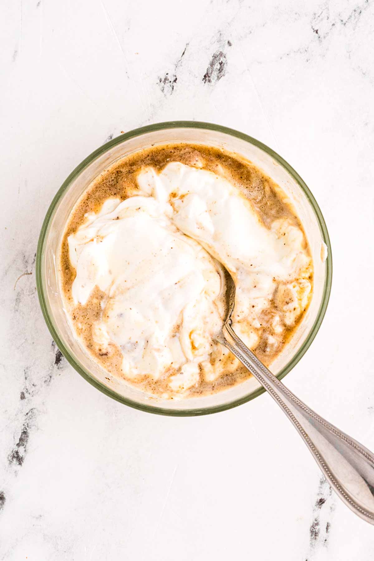 overhead view of sour cream in bowl with gravy and spoon