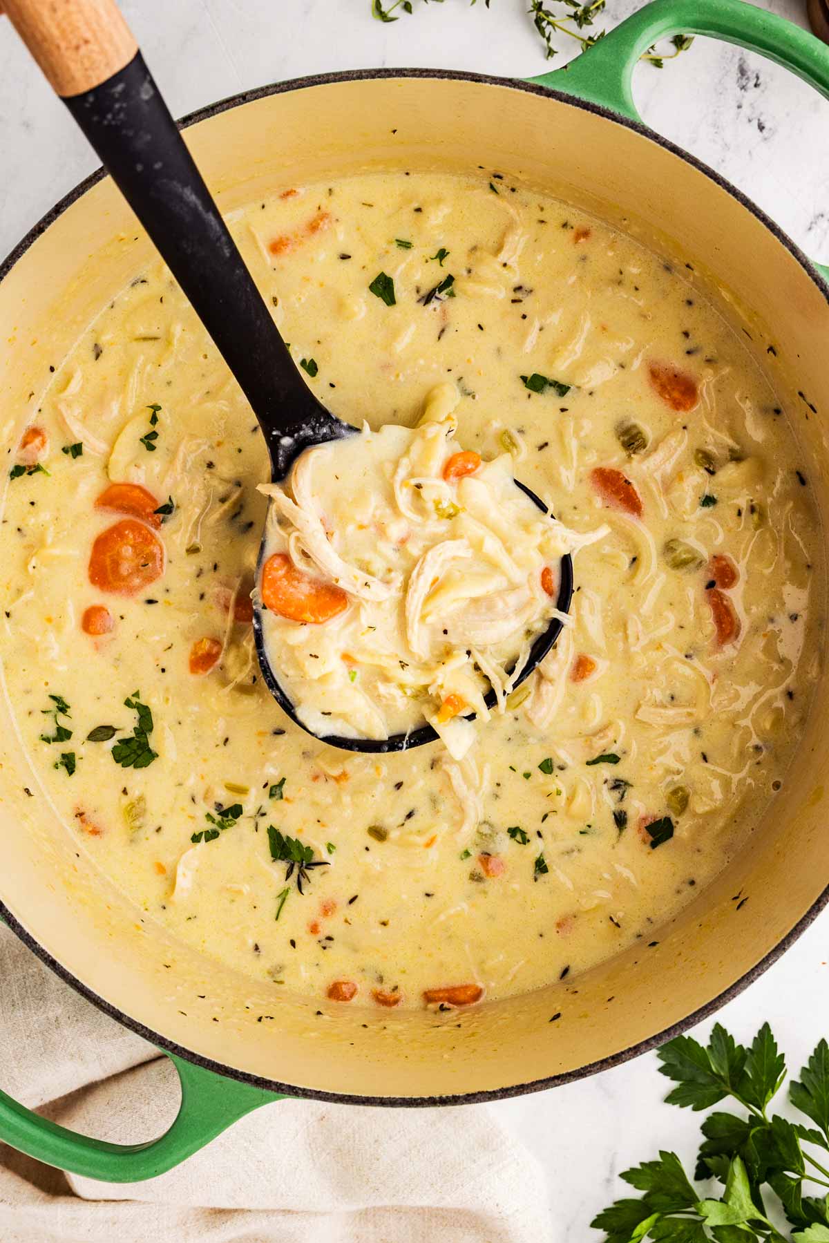 overhead view of creamy chicken noodle soup in a ladle