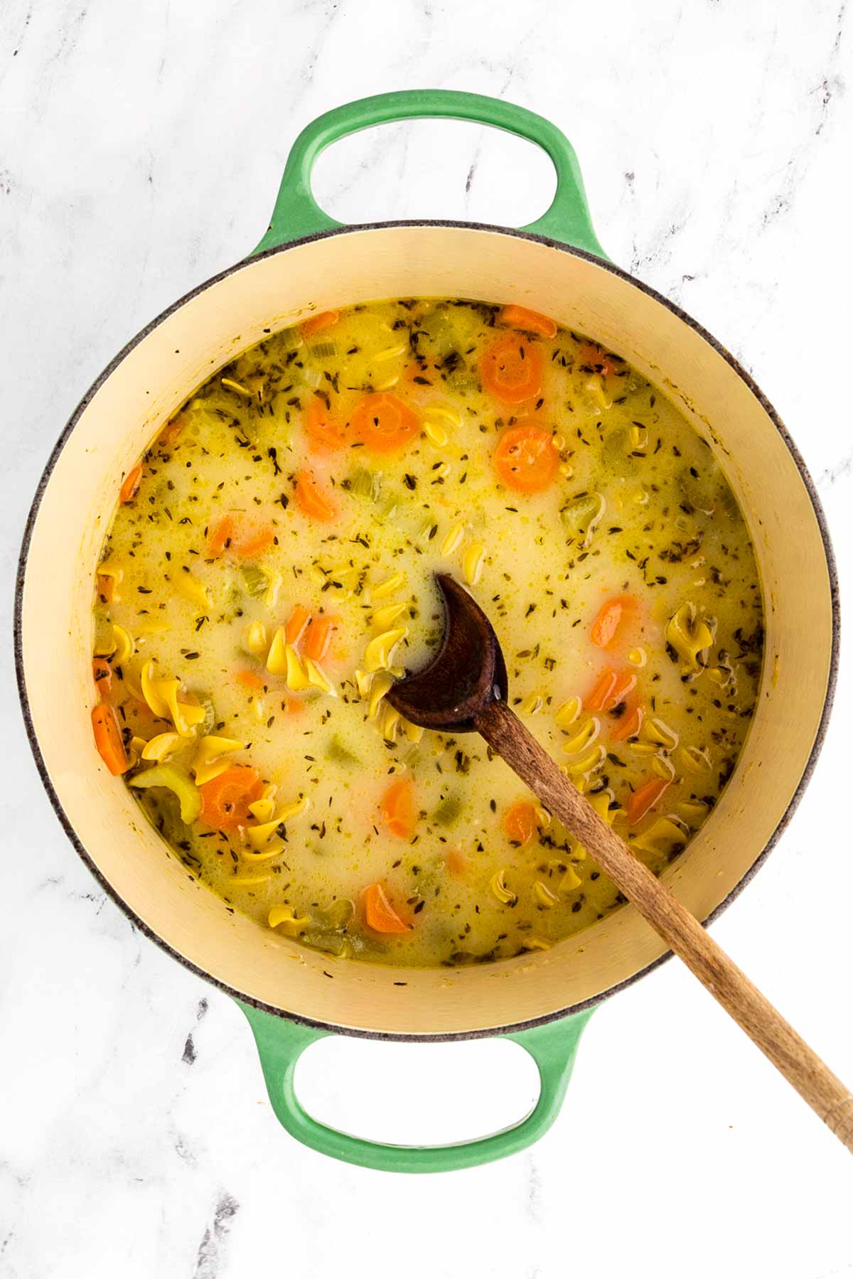 overhead view of soup with vegetables and noodles in Dutch oven