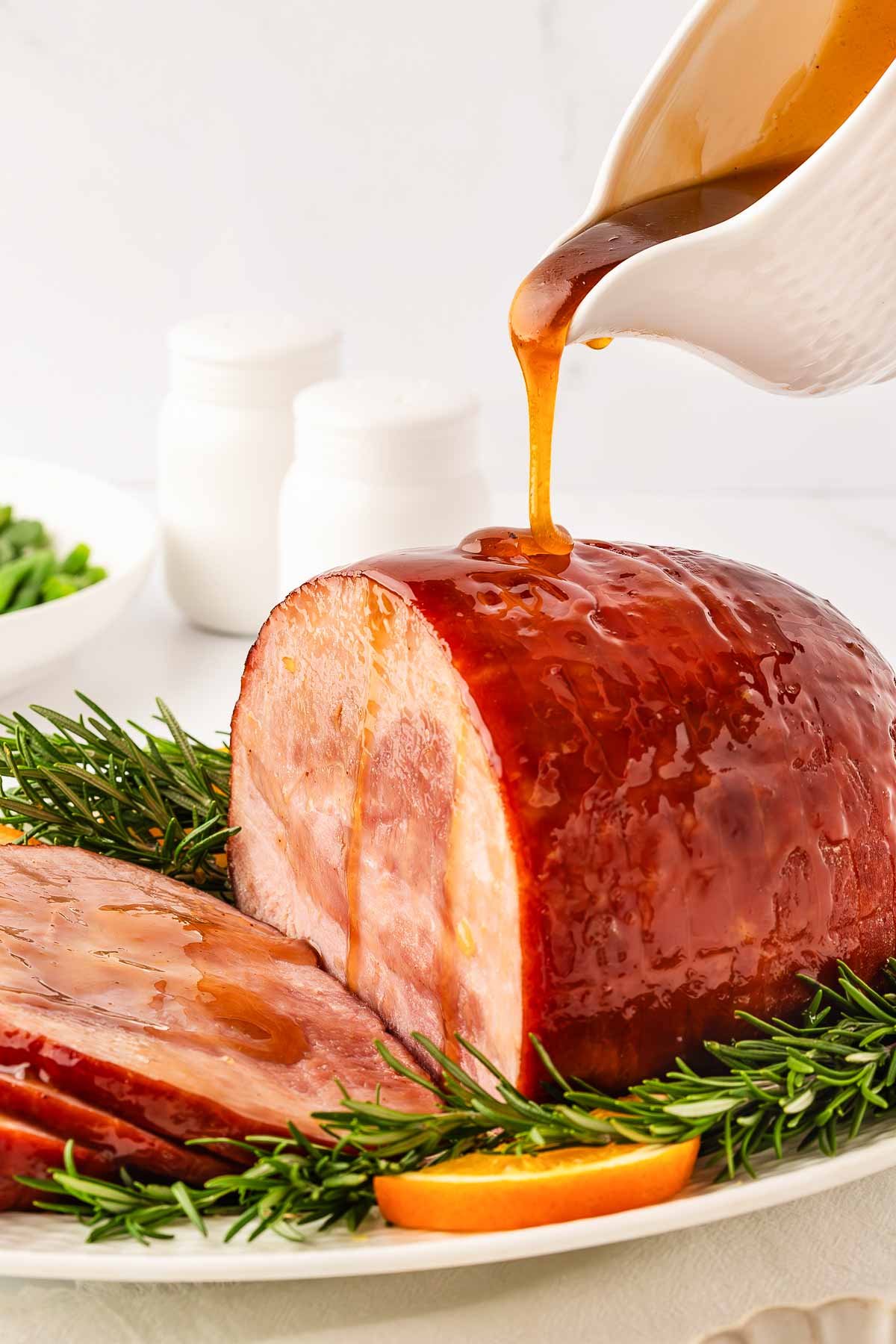 frontal view of sliced ham being drizzled with honey glaze