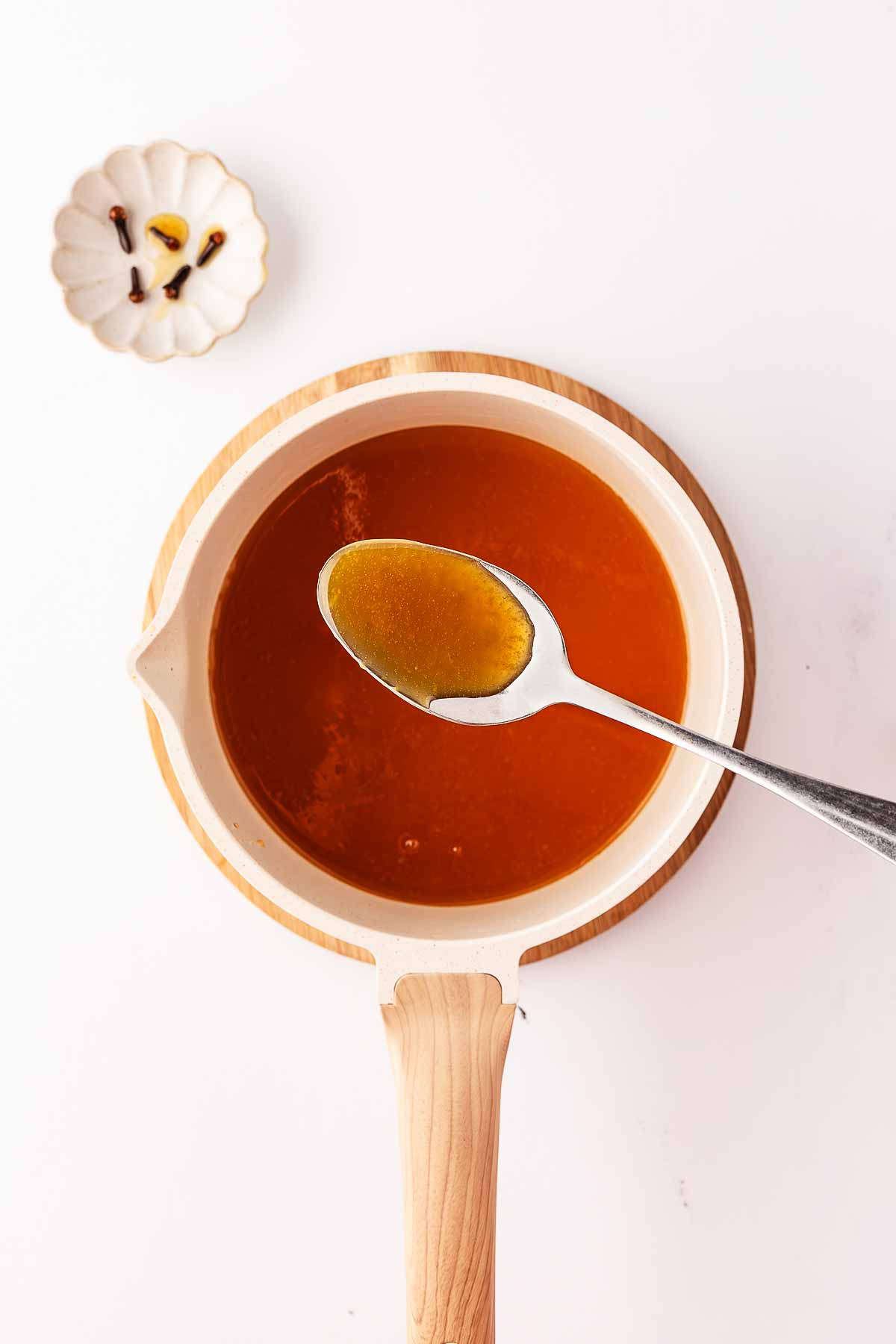 overhead view of honey glaze in white saucepan with spoon