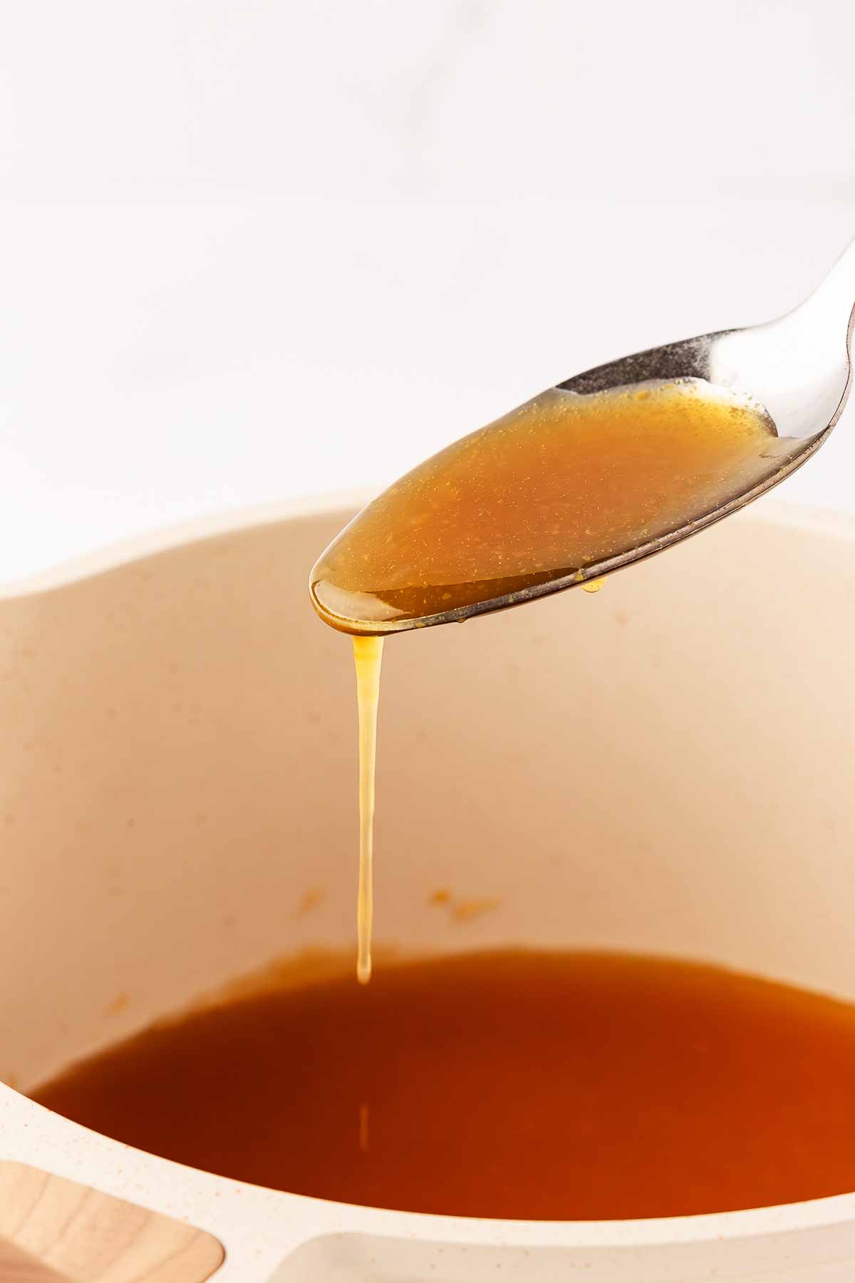 frontal close up view of honey glaze drizzling from spoon