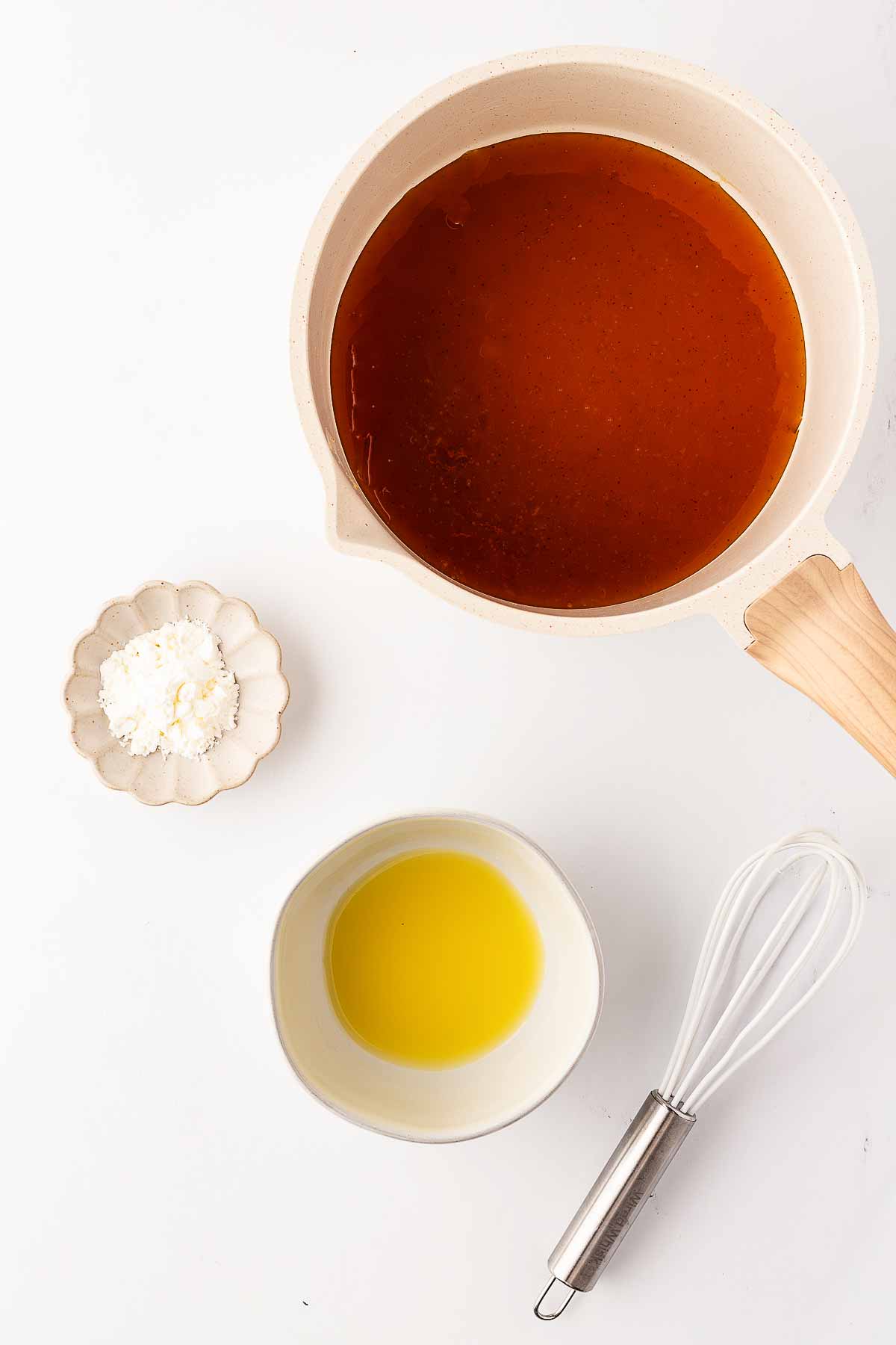 overhead view of saucepan with honey glaze next two bowls with orange juice and cornstarch