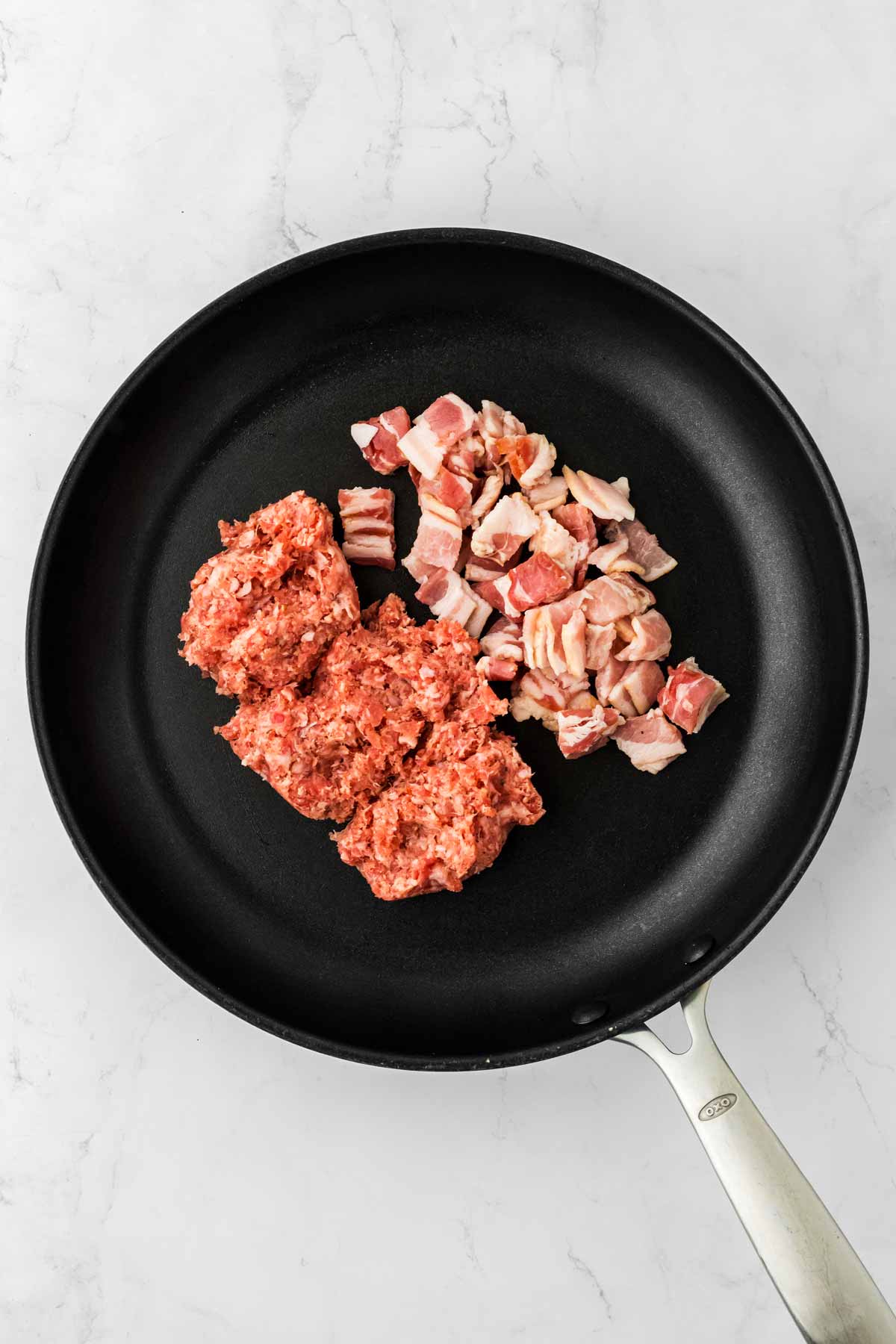 overhead view of breakfast sausage and diced bacon in skillet