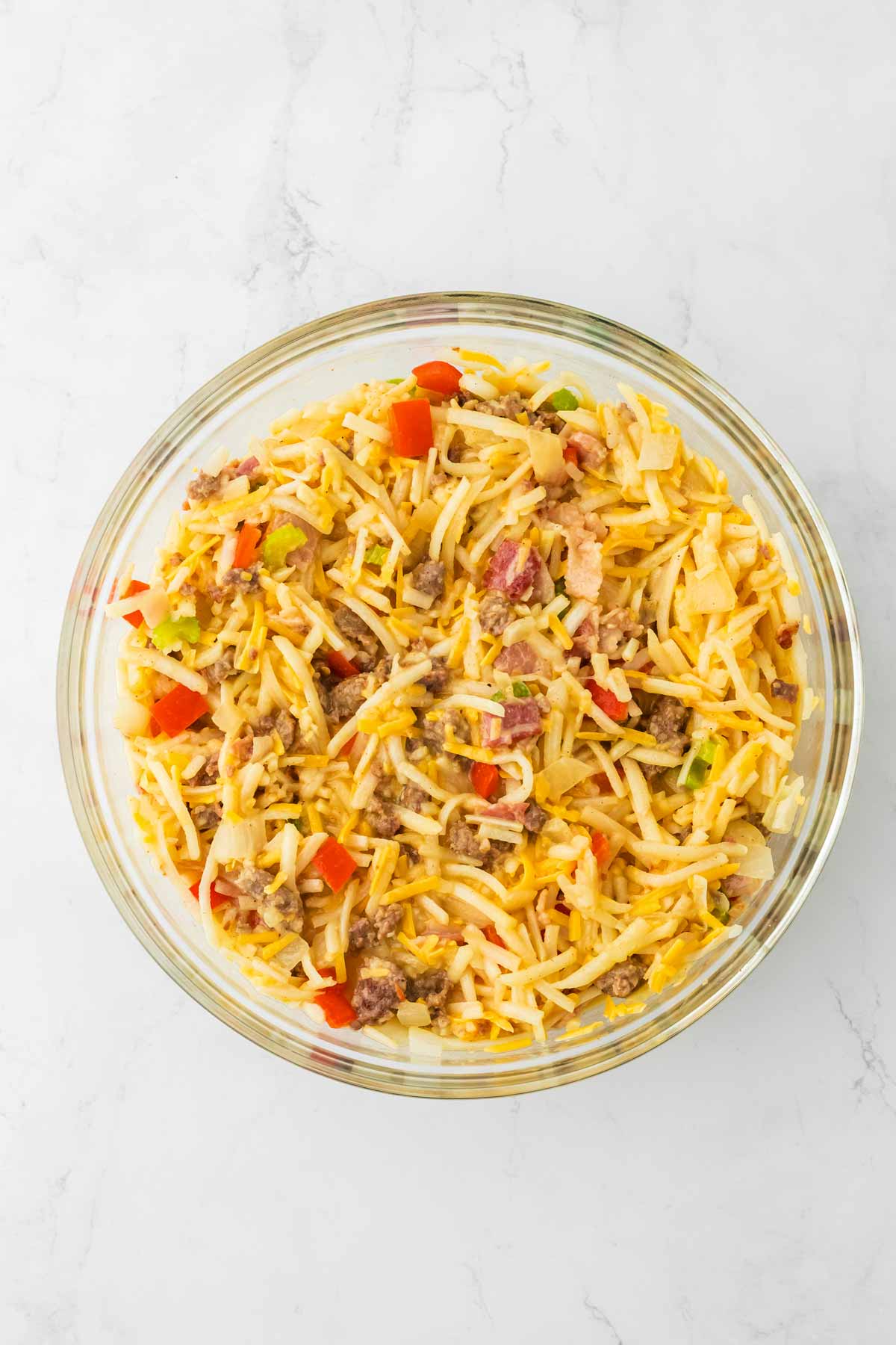 overhead view of hash brown casserole mixture in glass bowl