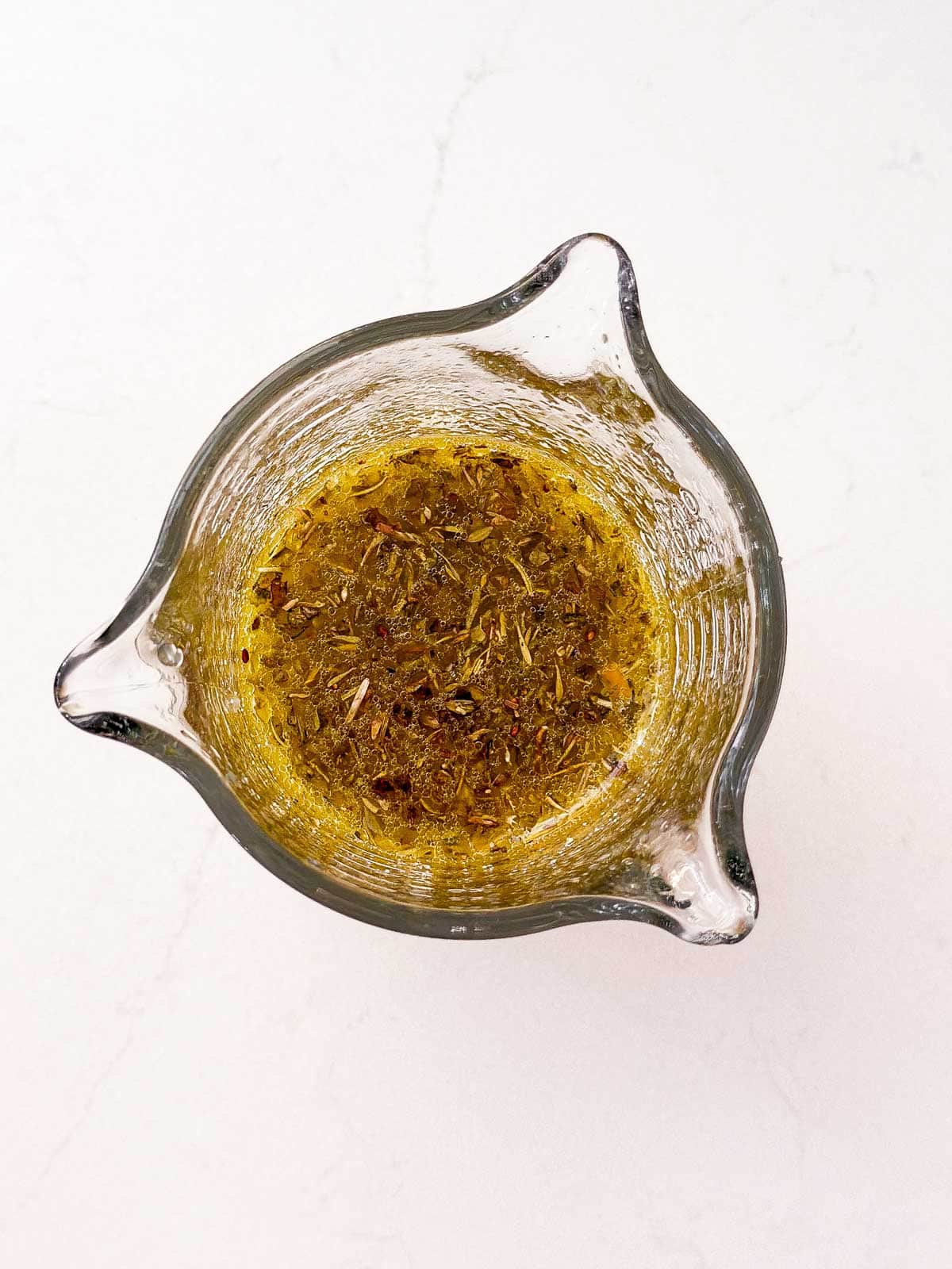 ovrehead view of lemon garlic chicken marinade in glass measuring jug