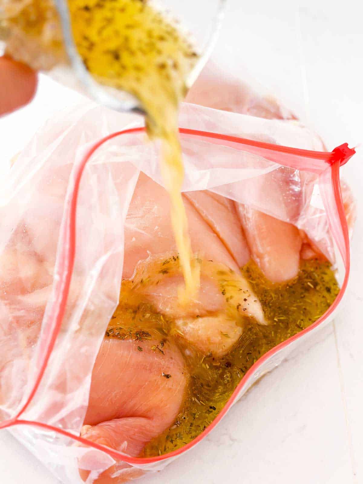 marinade pouring over chicken breast in ziptop bag