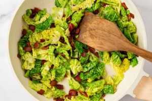 overhead view of cabbage and bacon cooking in skillet