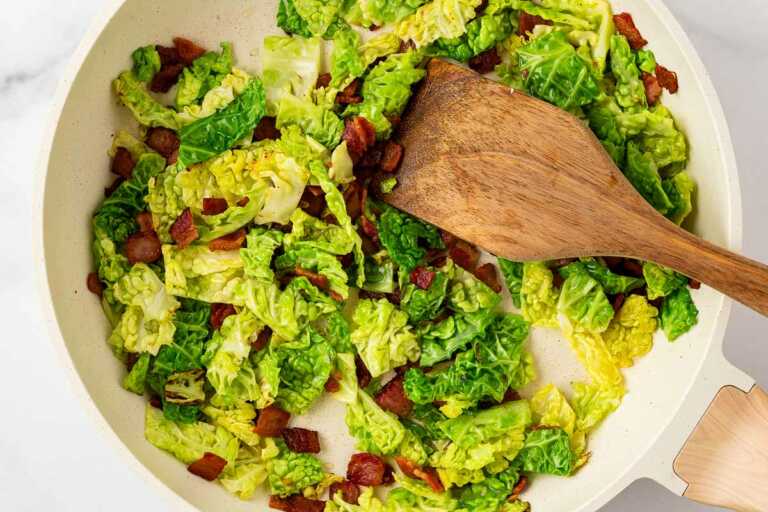 overhead view of cabbage and bacon cooking in skillet