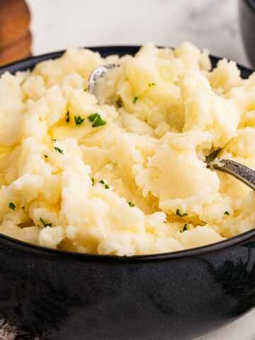 frontal view of mashed potatoes in black bowl