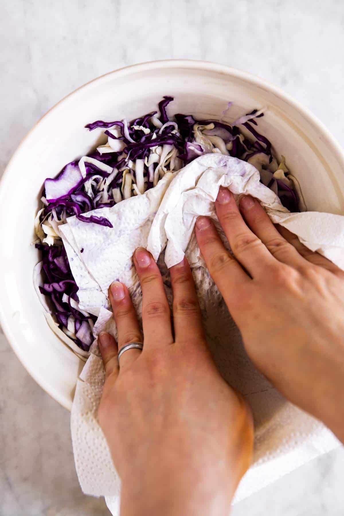 female hands patting dry cabbage in large mixing bowl