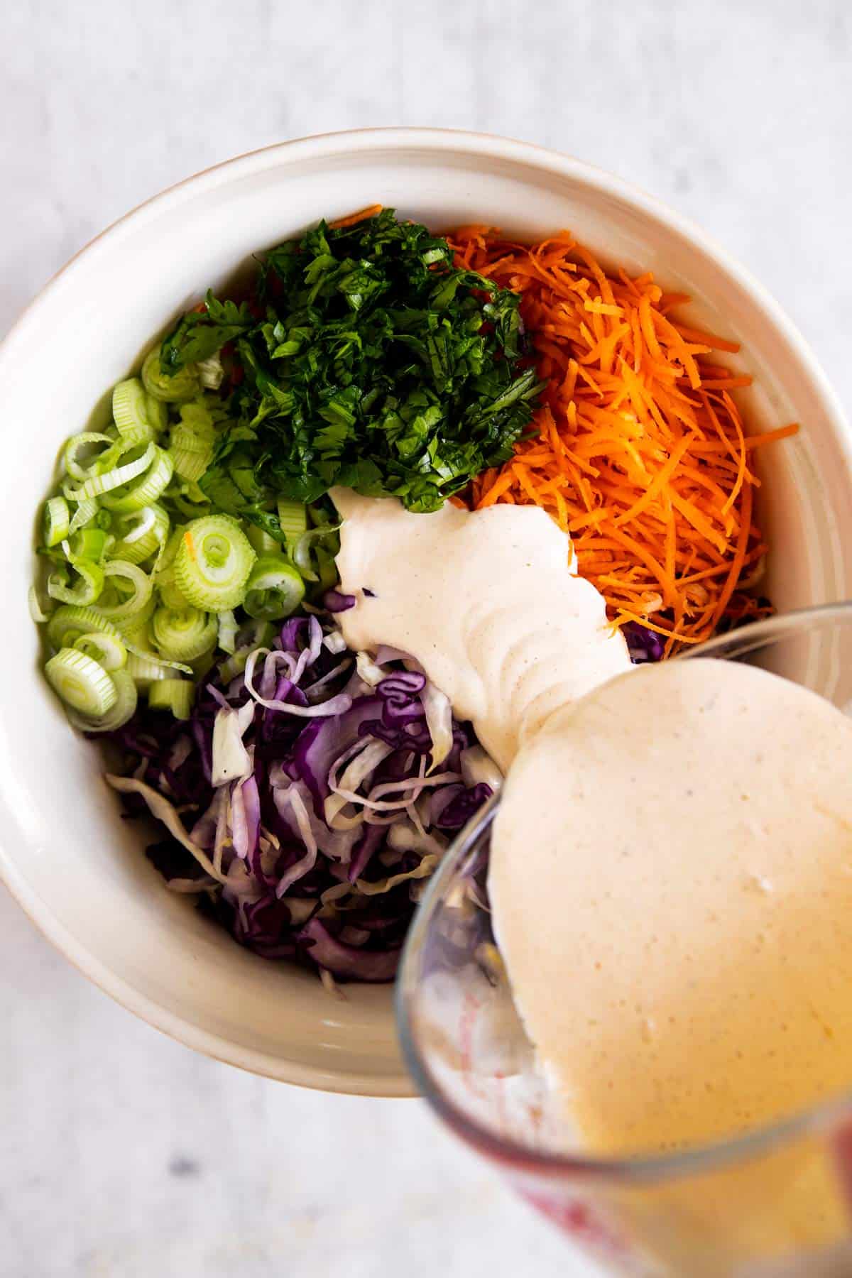 pouring dressing over coleslaw ingredients