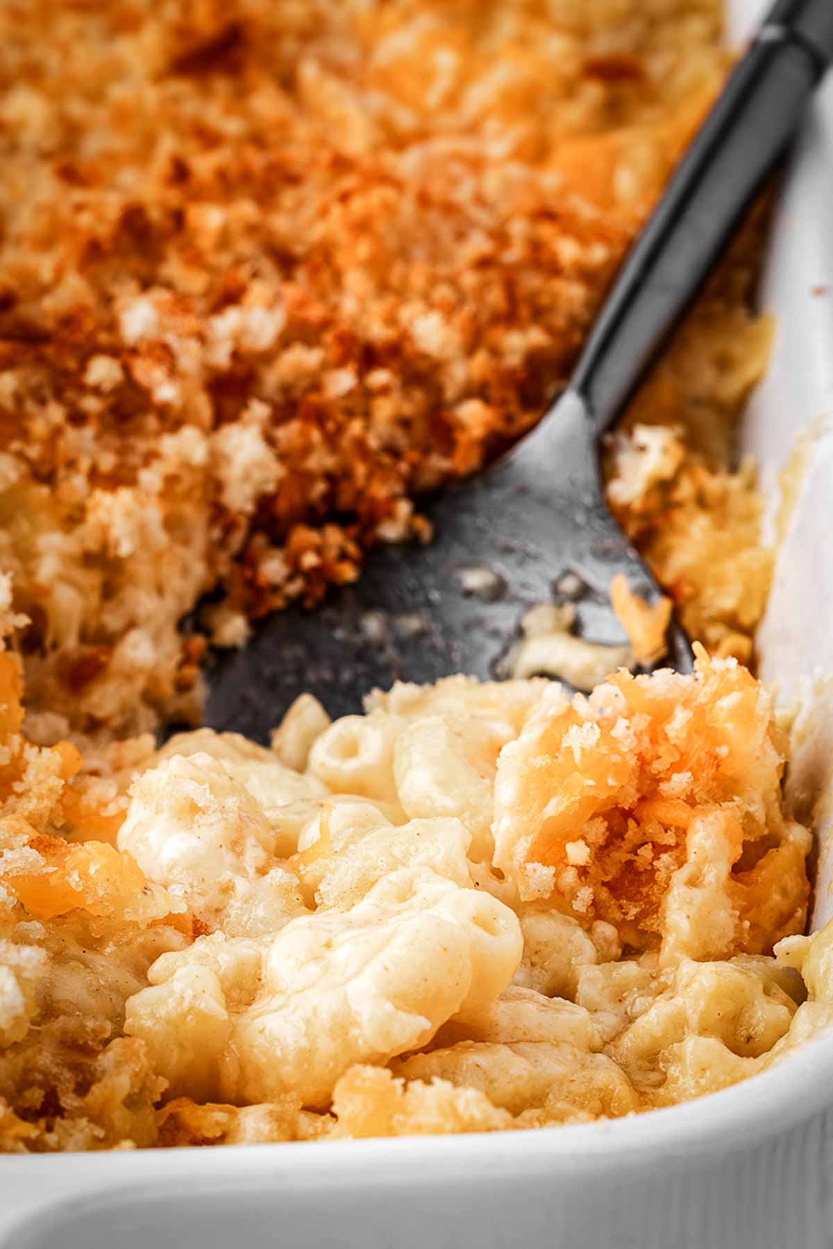 frontal view of Mac and cheese on spoon in casserole dish