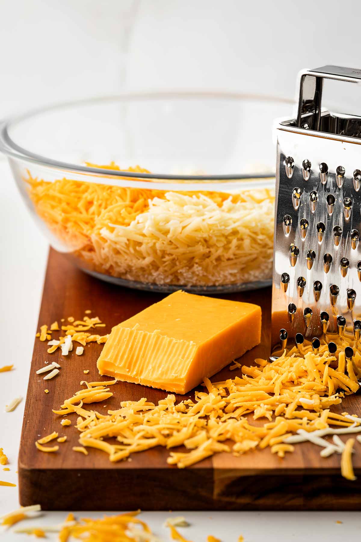 frontal view of cheese being shredded on wooden board