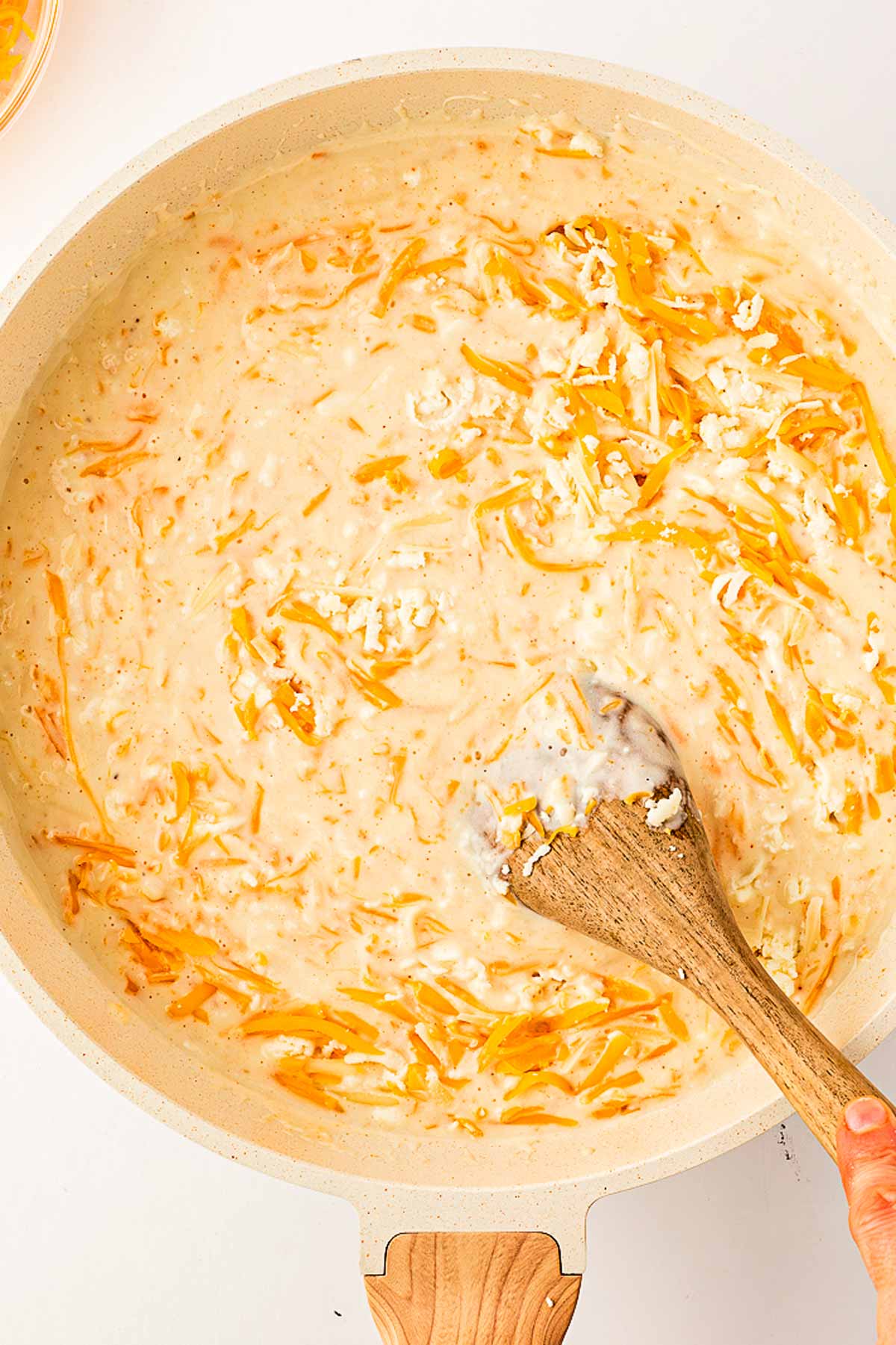 overhead view of cheese being stirred into béchamel sauce