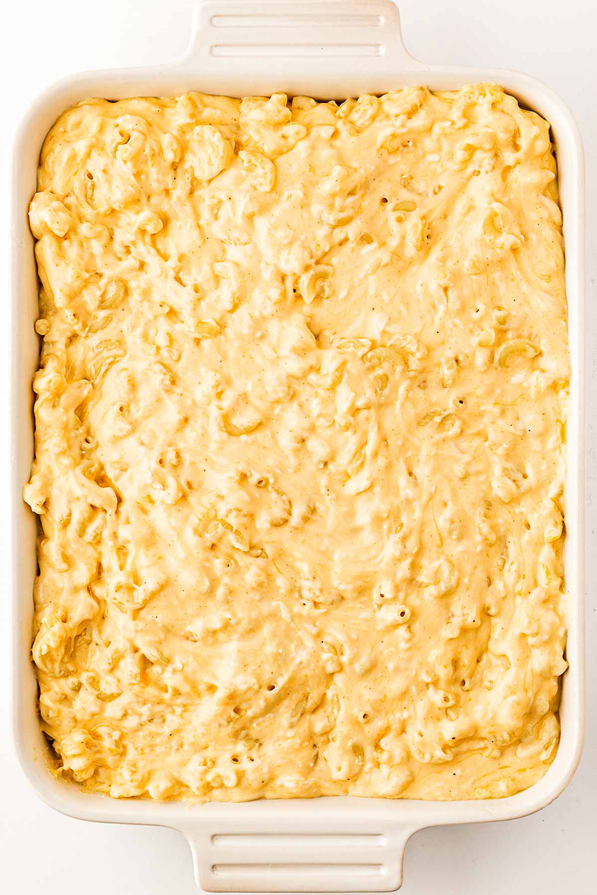 overhead view of unbaked macaroni and cheese sauce in white casserole dish